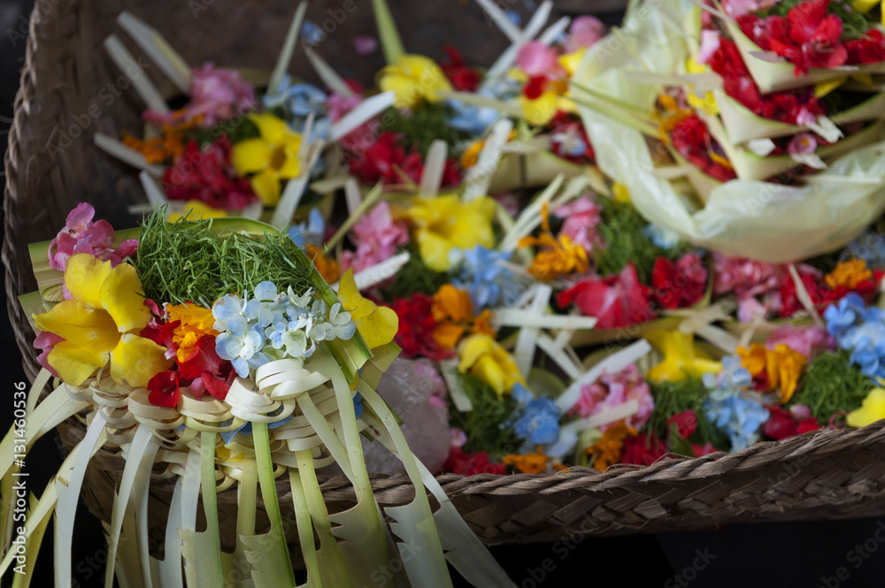 Colorful Balinese Hindu Offerings. Hindu offerings, called canang, are being made and sold at the Ubud village traditional public market. Flowers and palm leaves woven together make a beautiful piece.