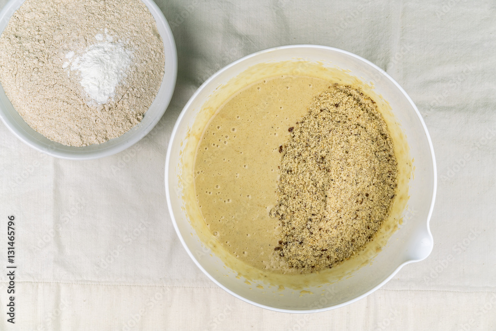 Overhead view of two bowls of healthy baking ingredients on light-colored tablecloth Overhead view of two bowls of healthy baking ingredients on light-colored tablecloth