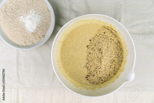 Overhead view of two bowls of healthy baking ingredients on light-colored tablecloth