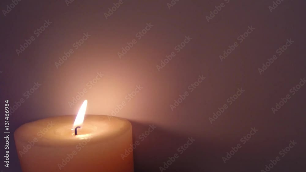 Candle flame flickering against the lower left corner of a neutral background