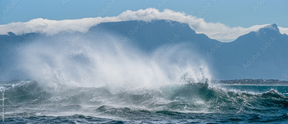 Seascape. Clouds sky, waves with splashes, mountains silhouettes. False bay. South Africa.