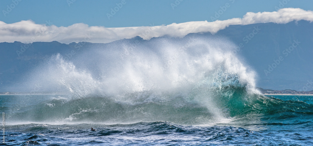 Fototapeta premium Seascape. Clouds sky, waves with splashes, mountains silhouettes. False bay. South Africa.