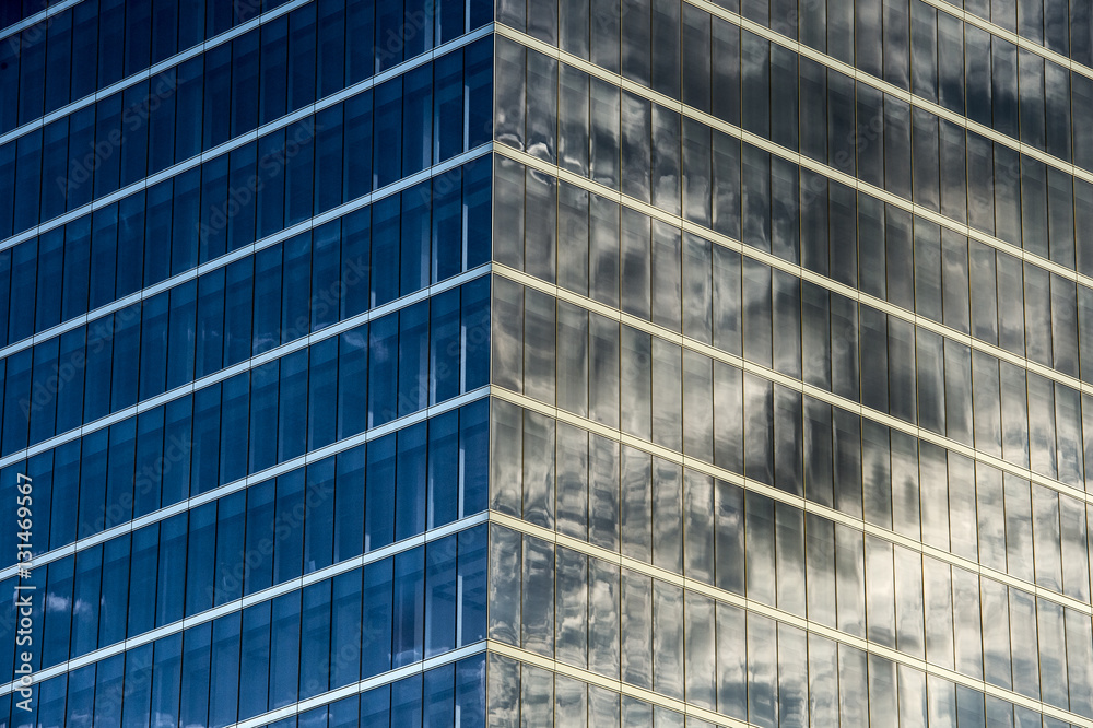 exterior corner of modern mostly glass office building with windows reflecting clouds exterior corner of modern mostly glass office building with windows reflecting clouds