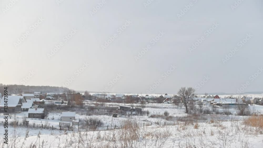 View of typical Russian village at winter - cold day in snow-covered field View of typical Russian village at winter - cold day in snow-covered field