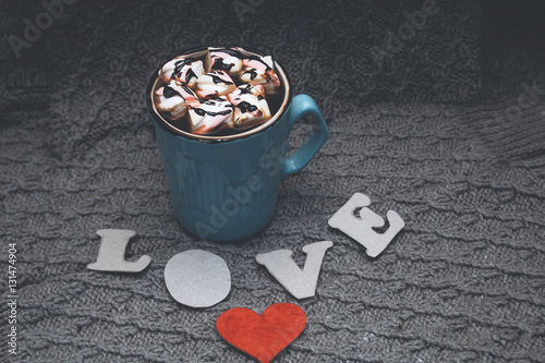 cocoa in blue mug, the letters LOVE and a little red cardboard heart on gray knitted background