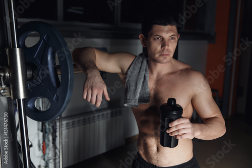 guy bodybuilder tired in gym hold shaker with sportive nutrition - protein of shaker.