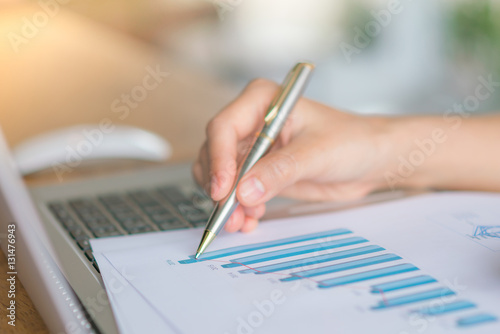 Business woman hand with Financial charts and laptop on the tabl
