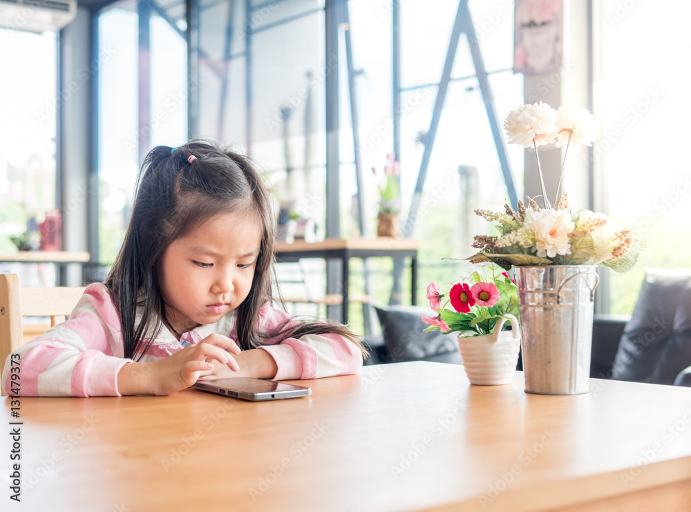 Portrait of Asia pretty little girl play mobile phone, serious f Portrait of Asia pretty little girl play mobile phone, serious f