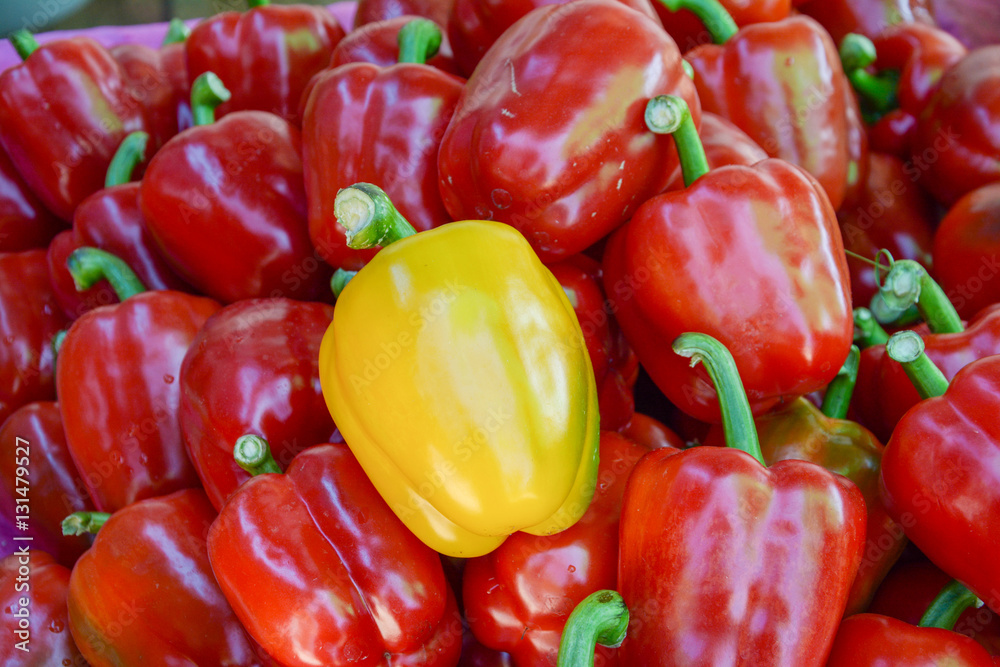 a yellow bell pepper in red bell peppers, different concept a yellow bell pepper in red bell peppers, different concept
