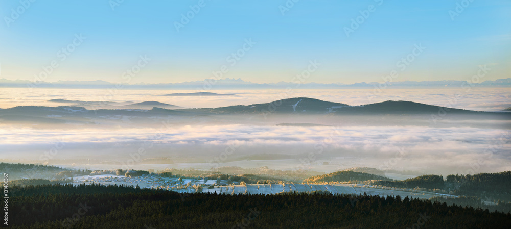 Panorama of the Alps from the tower Haidel in Bavaria. The magnificent panorama of the Alps. Villages and countryside in the fog lit by the morning sun.