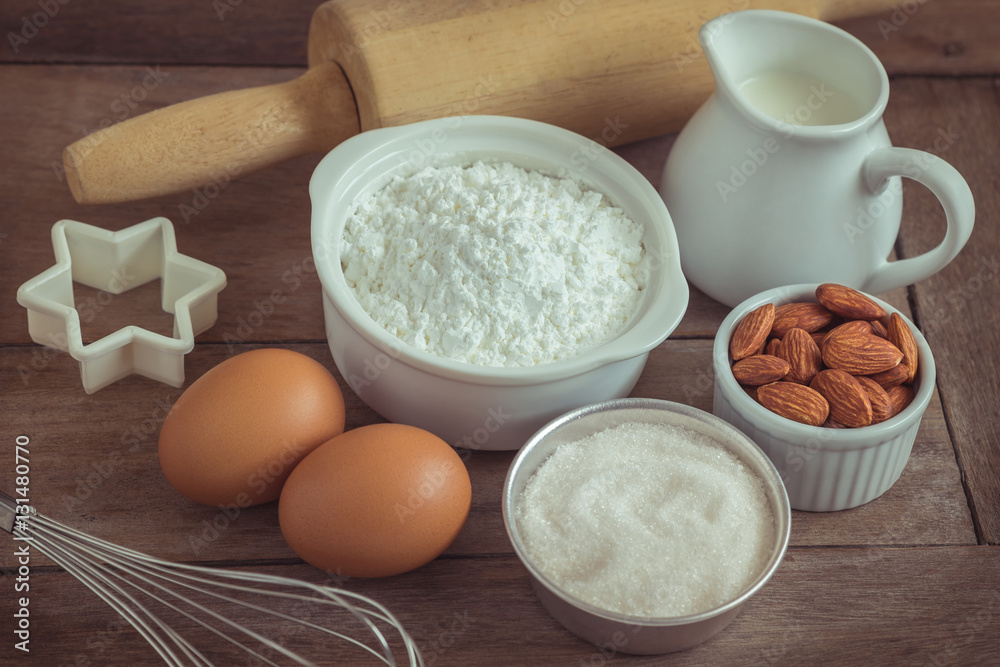 Baking ingredients flour, egg, milk, almonds, sugar on wooden table Baking ingredients flour, egg, milk, almonds, sugar on wooden table
