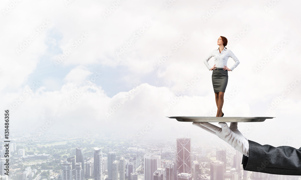 Confident elegant businesswoman presented on metal tray against cityscape background Confident elegant businesswoman presented on metal tray against cityscape background