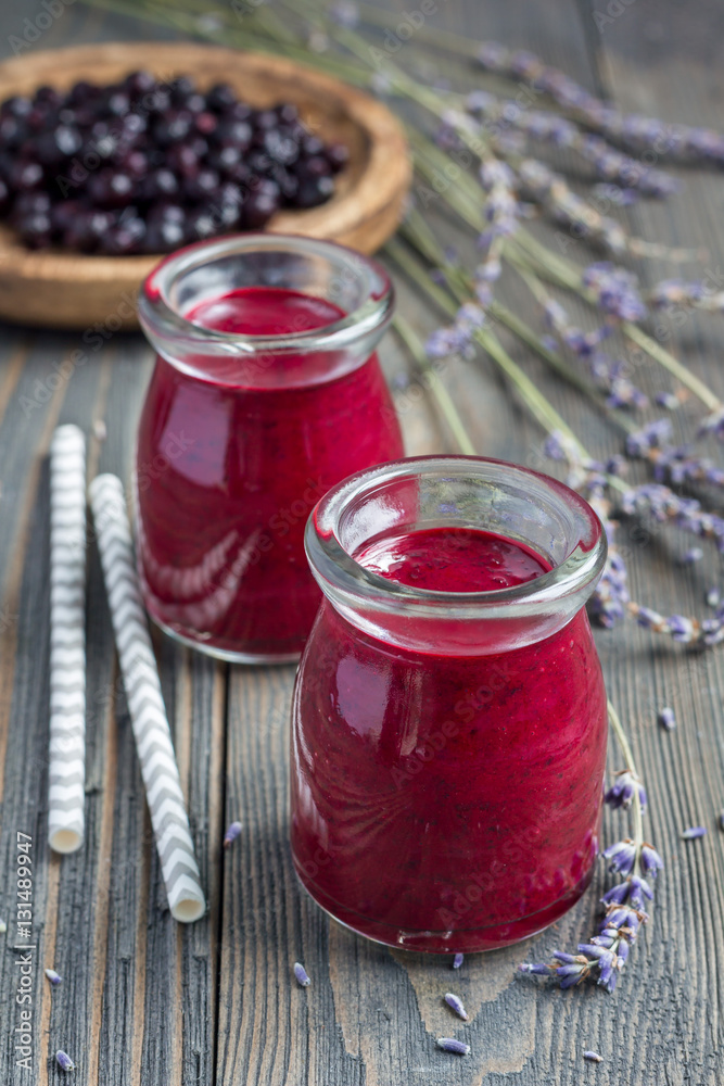 Black currant, greek yogurt, honey and lavender smoothie in glass jar with berries and flowers on background, vertical Black currant, greek yogurt, honey and lavender smoothie in glass jar with berries and flowers on background, vertical