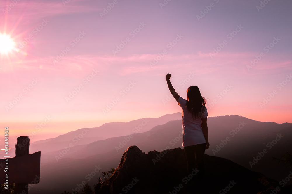 The silhouette of a woman in a yoga pose on the mountain at the Sunset.