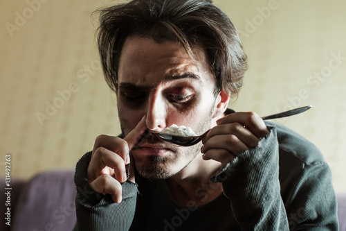 Addict in depression smells cocaine from a spoon photo