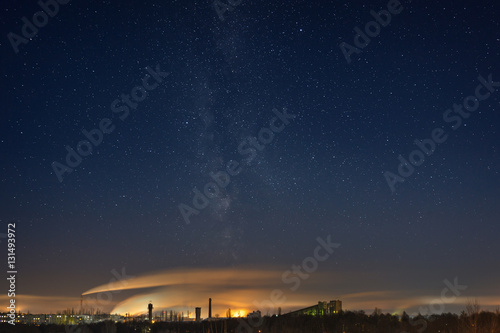 Night starry sky with the Milky Way over the industrial area of