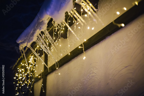 Snow-covered roof of a house decorated with garland