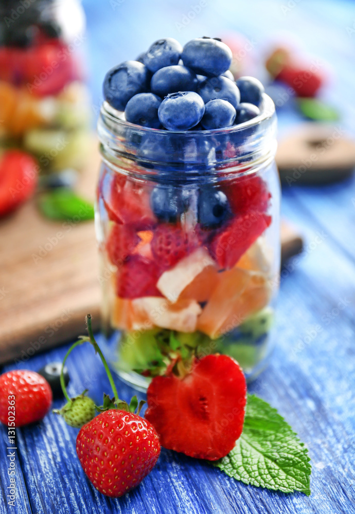 Glass jar with fruits and berries on wooden background Glass jar with fruits and berries on wooden background