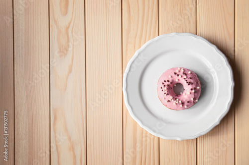 Plate with delicious donut on wooden background