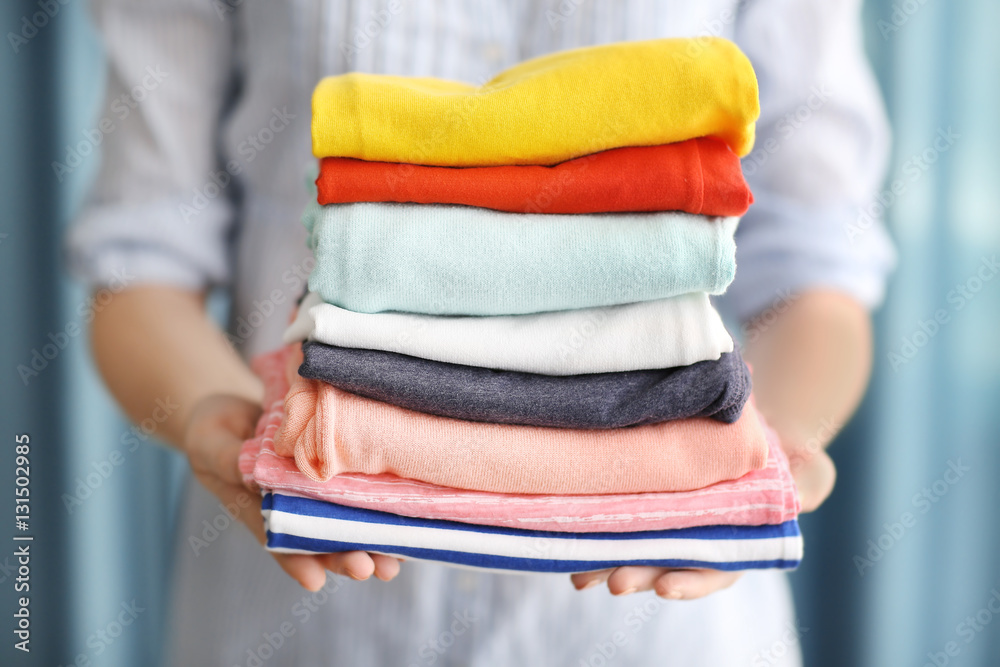 Woman holding stack of clothes, closeup Woman holding stack of clothes, closeup