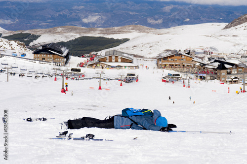 man lying on cold snow after ski crash at Sierra Nevada resort in Spain with mountains