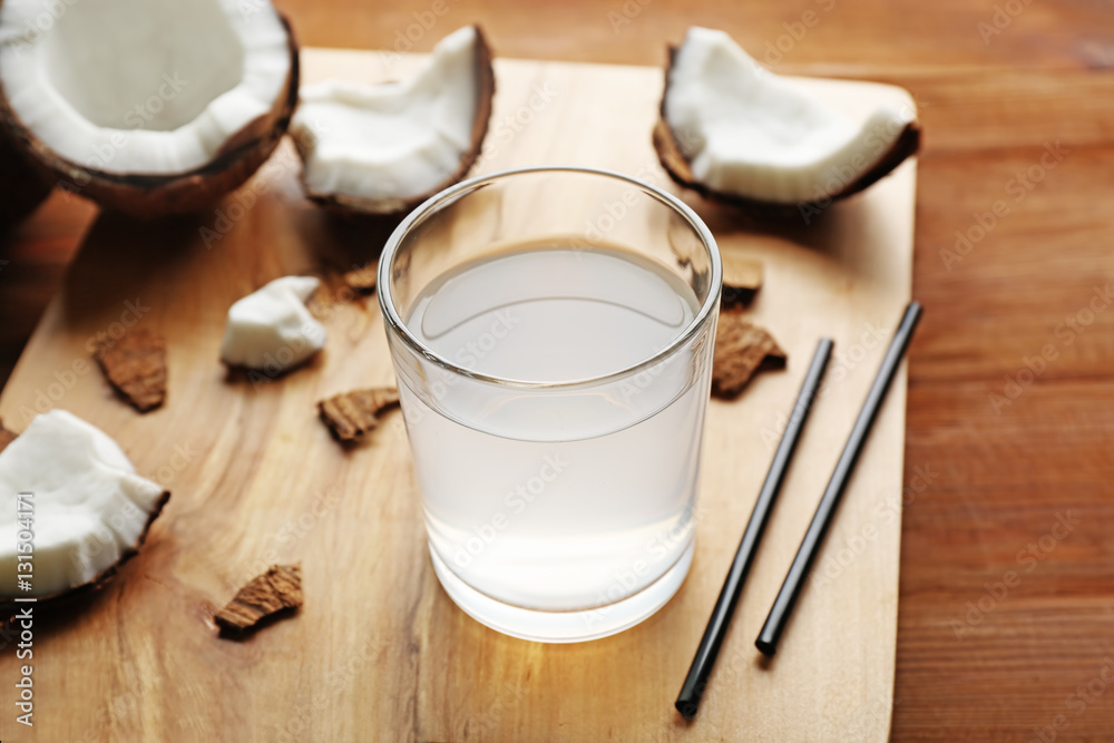 Glass of coconut water and fresh nuts on wooden board Glass of coconut water and fresh nuts on wooden board
