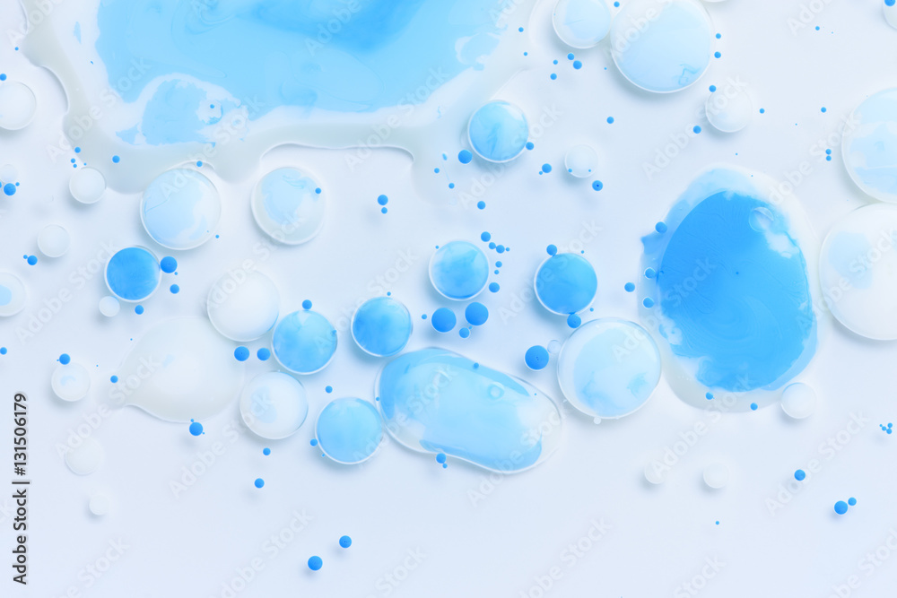 Abstract background with white and mixed blue paint drops in liquid