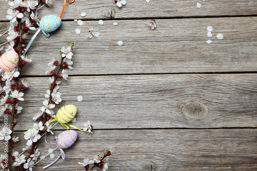 Tree branches with flowers and easter eggs on grey wooden table