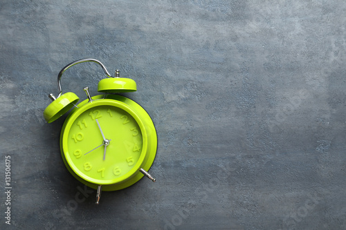 Green alarm clock on a grey wooden table photo