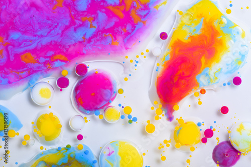 Colorful paint drops mixed in liquid on white background