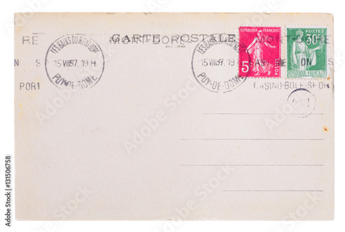 Vintage yellowed postcard back side, circa 1937, with old french post and meter stamps, with text Postcard and name of french village Mont Dore, isolated on white background