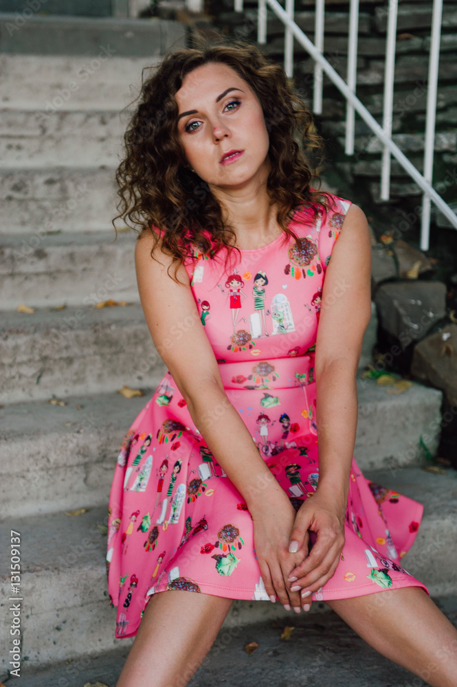 Beautiful brunette girl posing in pink dress outside near tropical plants Beautiful brunette girl posing in pink dress outside near tropical plants