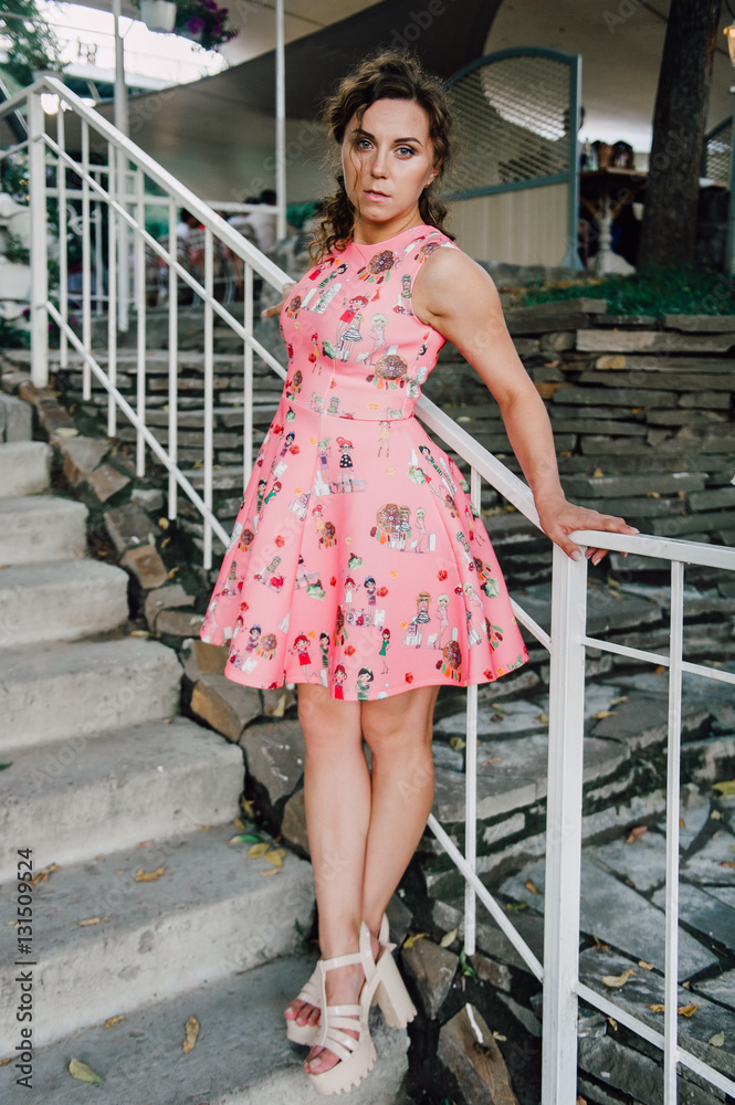 Beautiful brunette girl posing in pink dress outside near tropical plants Beautiful brunette girl posing in pink dress outside near tropical plants