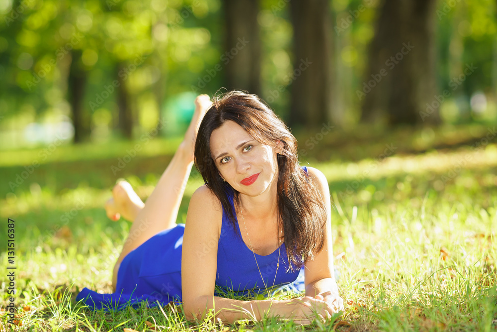 Beautiful happy young woman in blue dress lying on the grass Beautiful happy young woman in blue dress lying on the grass