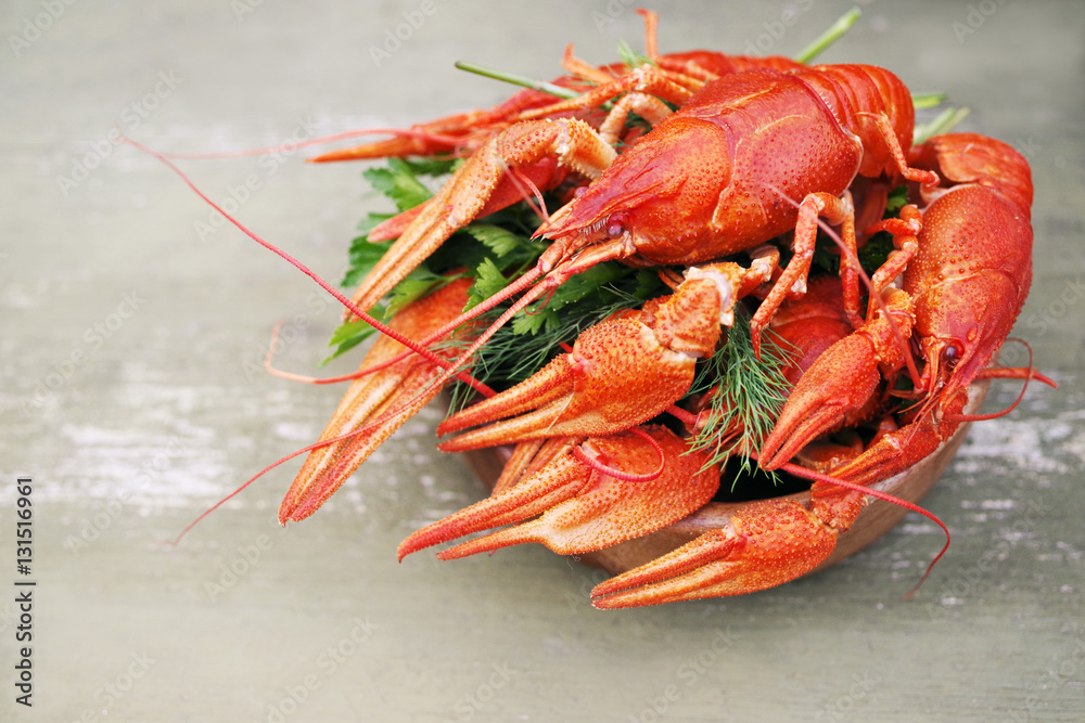 Boiled crayfishes in a round wooden plate on a wooden background, close up Boiled crayfishes in a round wooden plate on a wooden background, close up