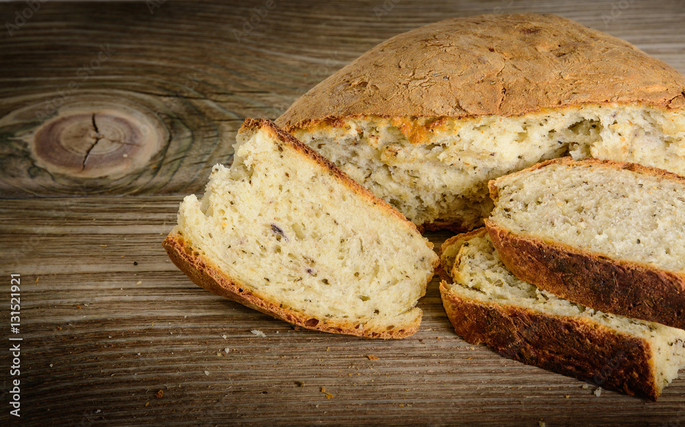 Sliced loaf of homemade bread made with herbs and spices on wooden background. Sliced loaf of homemade bread made with herbs and spices on wooden background.