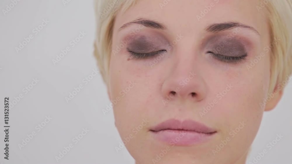 Professional make-up artist applies eye shadow to eyelid of model in white room. Beauty, makeup and fashion concept Professional make-up artist applies eye shadow to eyelid of model in white room. Beauty, makeup and fashion concept