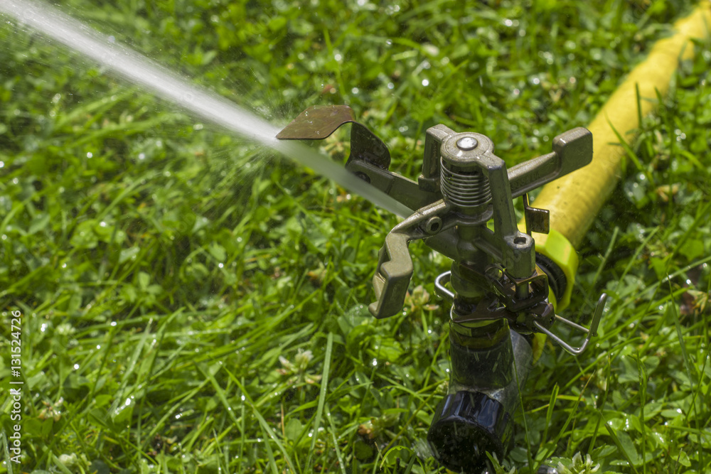 automatic sprinkler system watering the lawn on a background of green grass automatic sprinkler system watering the lawn on a background of green grass