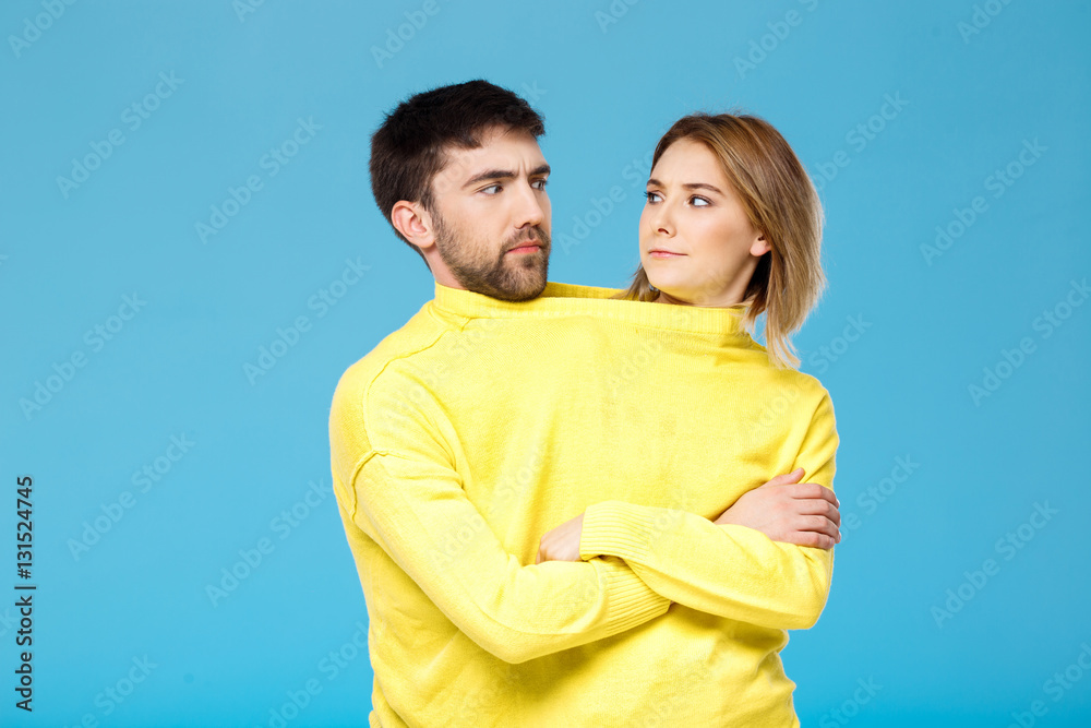 Couple in yellow sweater posing with crossed arms over blue background. Couple in yellow sweater posing with crossed arms over blue background.