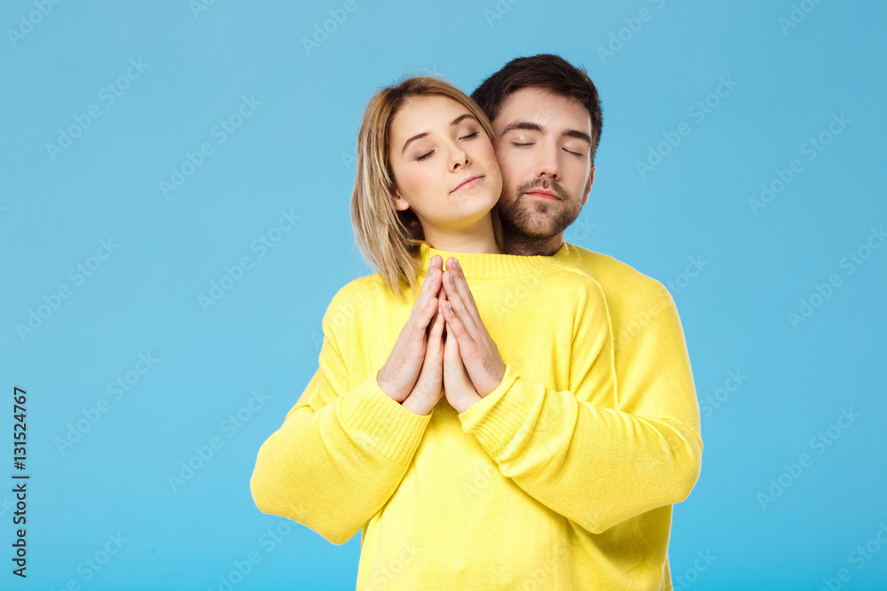Young beautiful couple in one yellow sweater embracing smiling over blue background. Young beautiful couple in one yellow sweater embracing smiling over blue background.