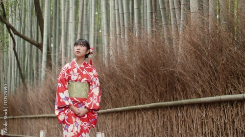 Beautiful Japanese Kimono girl walking through bamboo forest in Kyoto Japan 