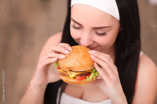 Young woman in a fine dining restaurant eat a hamburger, she behaves improperly
