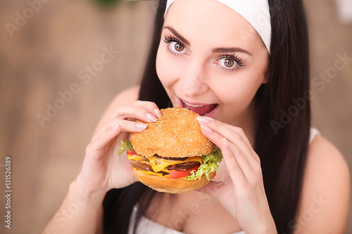 Young woman in a fine dining restaurant eat a hamburger  she behaves improperly
