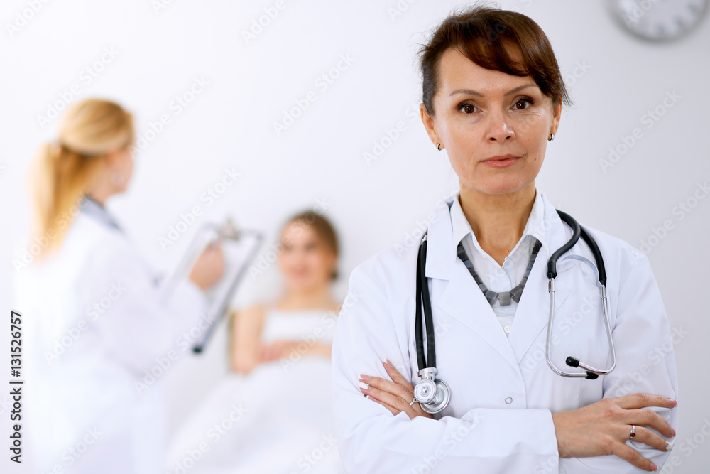 Female doctor smiling on the background with patient and his doctor Female doctor smiling on the background with patient and his doctor