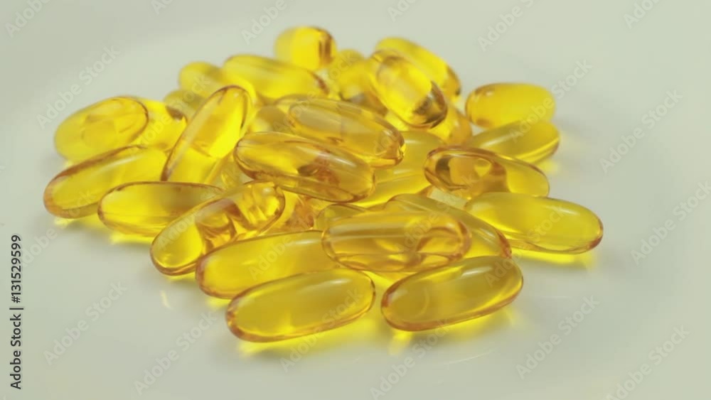 Pills rotate on white background. Vitamin E or fish oil yellow capsules Pills rotate on white background. Vitamin E or fish oil yellow capsules