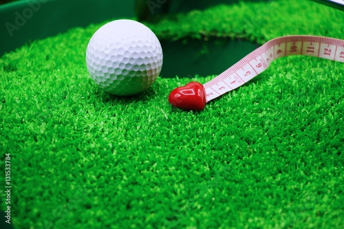 golf ball with red heart on green background