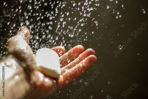 Open human hand with soap under water drops