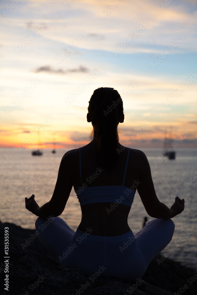Woman meditating in a yoga pose on the beach Woman meditating in a yoga pose on the beach
