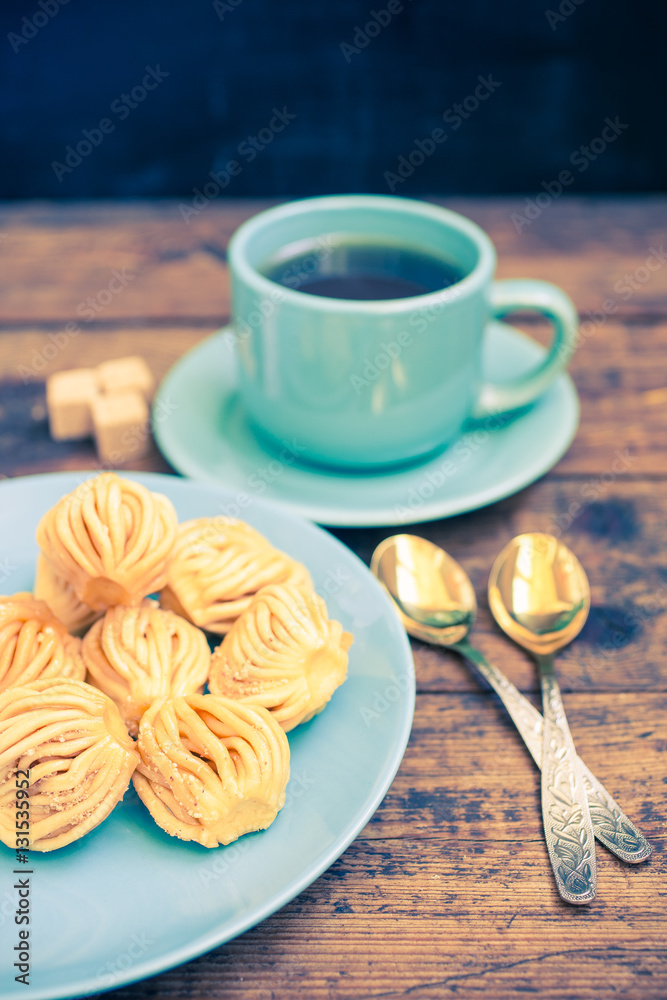 cookies in a plate and tea in a cup on a table, selective focus, the image are tinted