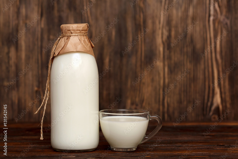 Bottle of milk and cup on rustic wooden table Bottle of milk and cup on rustic wooden table